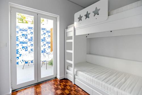 a white bedroom with a bunk bed and a sliding glass door at Historic Town Cascais Modern Apartment in Cascais