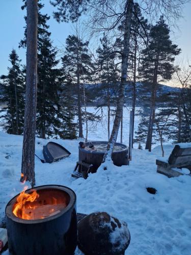 a fire pit with a tent in the snow at Typisk norsk off-grid hytte opplevelse in Levanger
