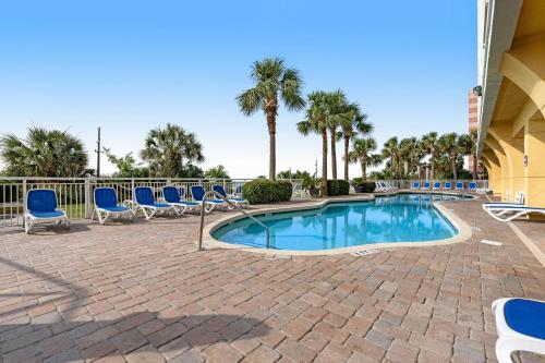 a swimming pool with blue chairs and palm trees at Camelot by the Sea - Oceana Resorts Vacation Rentals in Myrtle Beach