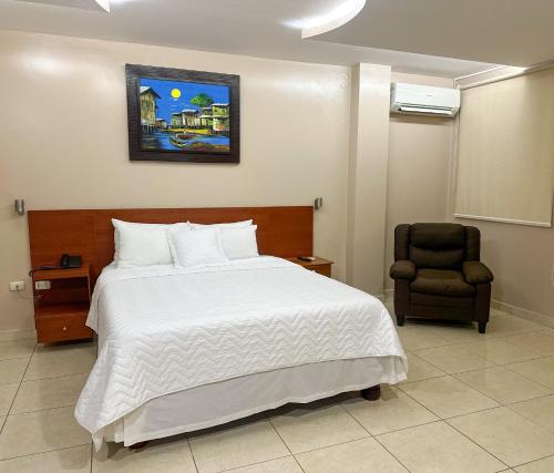 a bedroom with a white bed and a chair at Hotel Bucaneiro in Manta