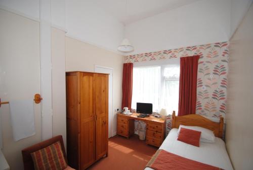 
a bedroom with a bed and a desk at The Curraghmore in Shanklin

