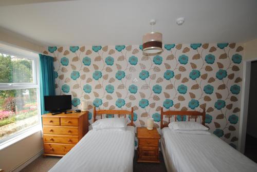 
a bedroom with two beds and a window at The Curraghmore in Shanklin
