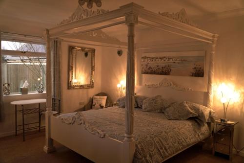 a bedroom with a white canopy bed with a mirror at Hot Tub Hideaway in Hemyock