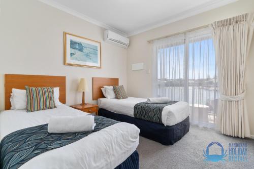 a hotel room with two beds and a window at Villa 55 by the Waters Edge in Mandurah