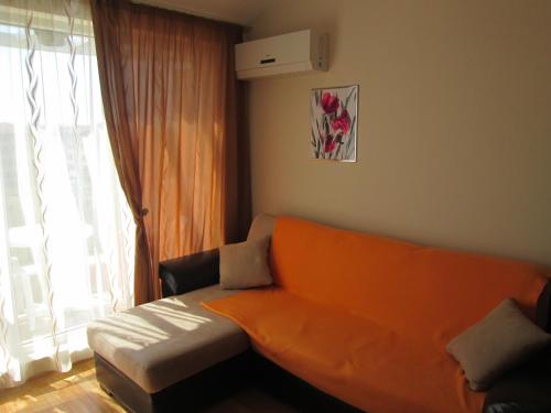 ラブダにあるMellia Boutique Apartmentsの窓付きのリビングルーム(オレンジ色のソファ付)