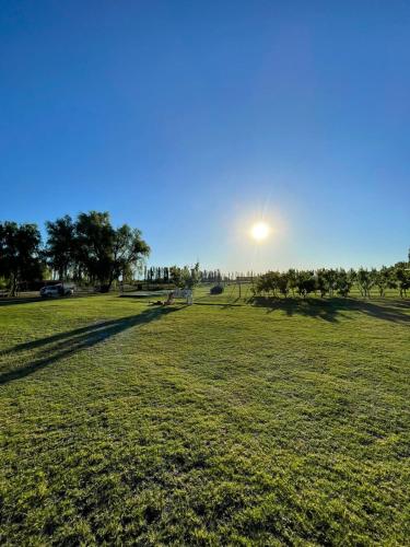 a field of grass with the sun in the sky at Las Potrancas cabaña in General Alvear