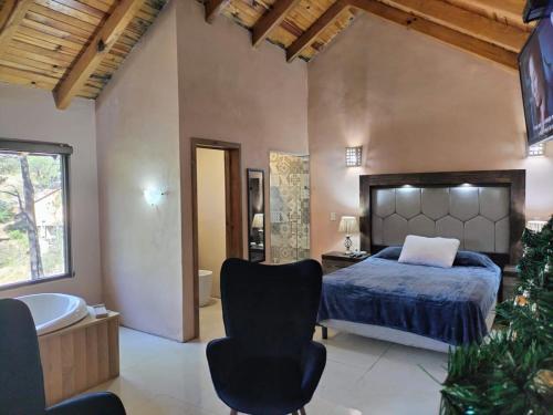 1 dormitorio con cama, bañera y silla en Cabaña para 2 Giuseppe en Bosque., en Mazamitla