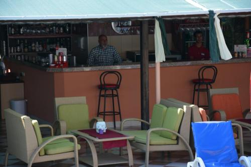 a man standing behind a bar with chairs and a table at Yavuzhan Hotel in Side