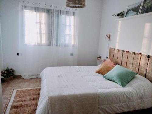 1 dormitorio con 1 cama grande con sábanas blancas y ventana en La Casita de Ari en Frontera