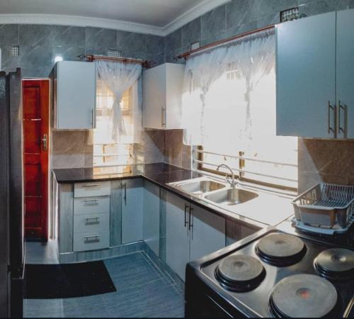 a kitchen with white cabinets and a stove top oven at Scolt Apartments Livingstone in Livingstone