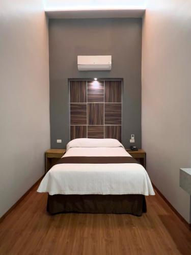 a bedroom with a large bed and wooden floors at Hotel Principal in Mexico City