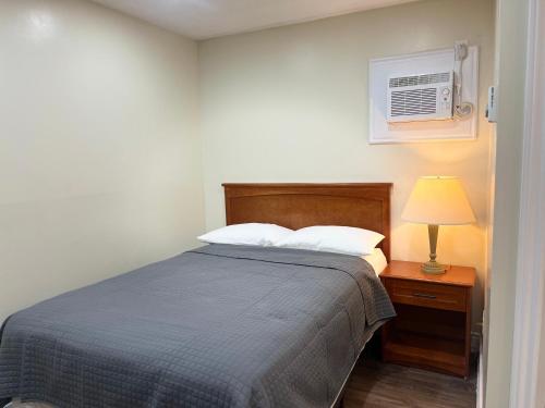 1 dormitorio con cama, lámpara y aire acondicionado en Cedar Springs Motel, en Acton