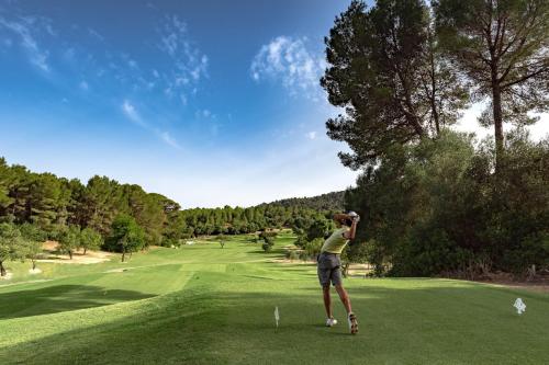 a woman is standing on a golf course at Castillo Hotel Son Vida, a Luxury Collection Hotel, Mallorca in Palma de Mallorca