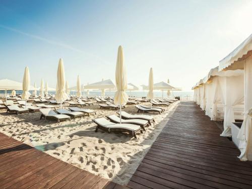 einen Strand mit Liegestühlen und Sonnenschirmen auf dem Sand in der Unterkunft Sofitel Grand Sopot in Sopot