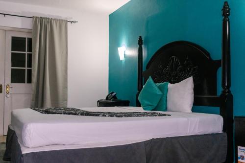 a bedroom with a bed with a blue wall at Grand Hotel Excelsior Port Royal in Kingston
