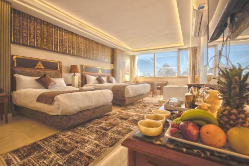 um quarto de hotel com duas camas e uma mesa com frutas em The Muse Pyramids Inn Hotel no Cairo