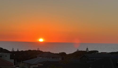 a sunset over the ocean with houses and buildings at Lagoon Drive Yanchep in Yanchep