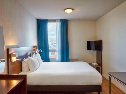 a hotel room with a large bed and a window at Aparthotel Adagio Access Paris Saint-Denis Pleyel in Saint-Denis