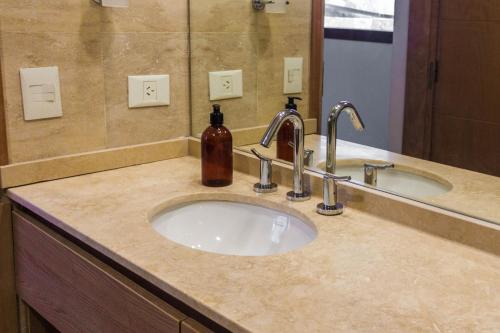 a bathroom counter with a sink with a bottle of soap at LA TUA CASA in San Carlos de Bariloche