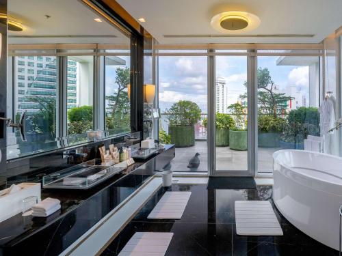 ein Badezimmer mit einer großen Badewanne und einem großen Fenster in der Unterkunft Novotel Manila Araneta City Hotel in Manila