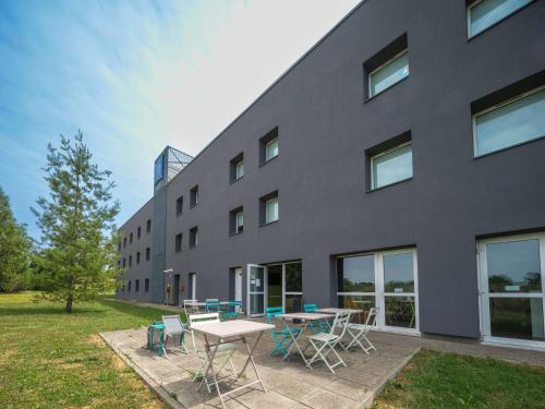 een gebouw met een tafel en stoelen ervoor bij Ibis Budget Sarrebourg Buhl in Sarrebourg