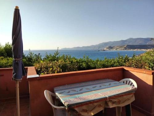 a table and chairs with an umbrella and the ocean at MAREVIGLIOSO Fronte Mare Sea Front in Magomadas