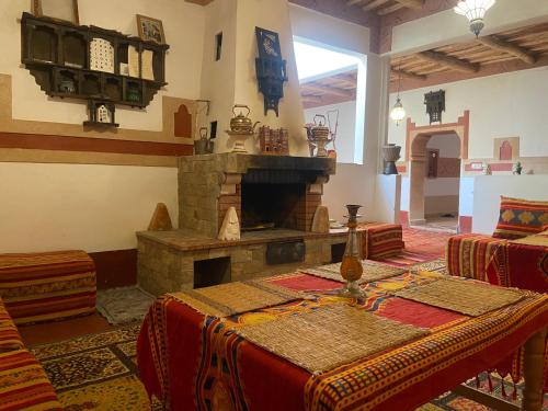 a living room with a stone fireplace and a table at Tafsut dades guesthouse stay with locals in Tamellalt