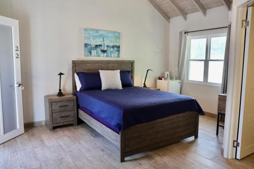 a bedroom with a blue bed and a window at The Moxy in English Harbour Town