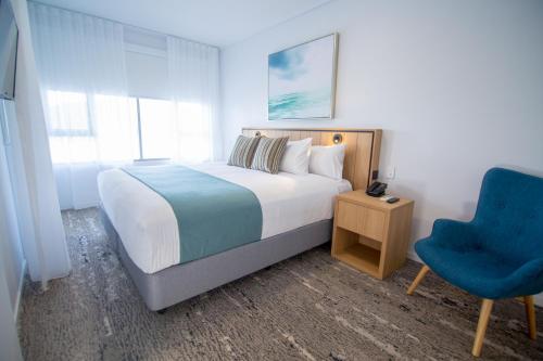 a bedroom with a bed and a blue chair at Club Wyndham Airlie Beach in Airlie Beach
