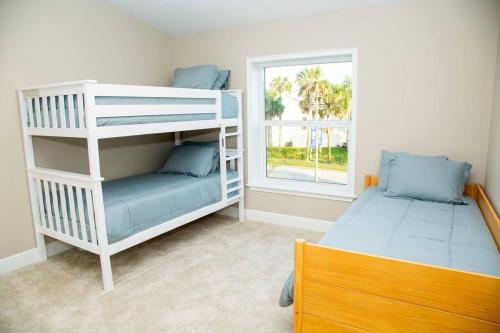 デイトナ・ビーチ・ショアーズにある6 BEDROOMs - Walk to Beach - Garagesのベッドルーム1室(二段ベッド2台、窓付)が備わります。