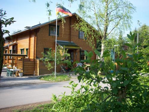 una casa de madera con una bandera delante de ella en Ferienhaus-Hotel "Zur Grünen Oase", en Adelmannsfelden