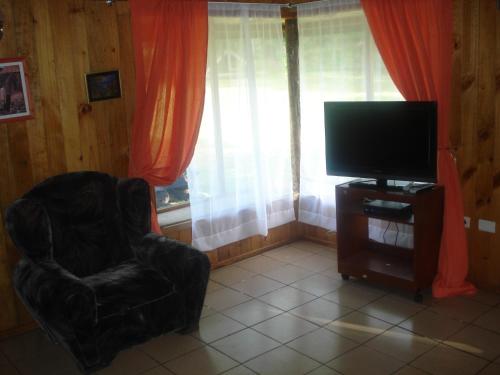 ein Wohnzimmer mit Sessel und Fernseher in der Unterkunft Cabañas Pichares in Caburgua