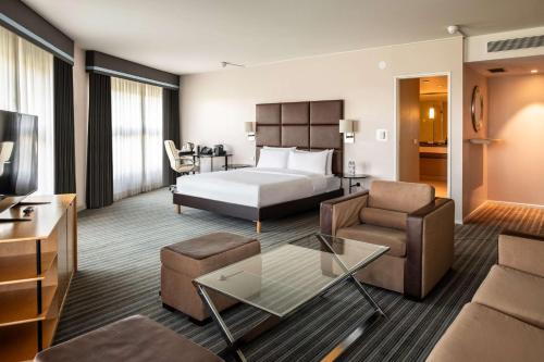 ロワシー・アン・フランスにあるThe Atrium Hotel & Conference Centre Paris CDG Airport, by Pentaのベッドとリビングルームが備わるホテルルームです。