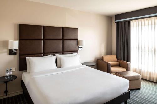 a hotel room with a large bed and a chair at The Atrium Hotel & Conference Centre Paris CDG Airport, by Penta in Roissy-en-France
