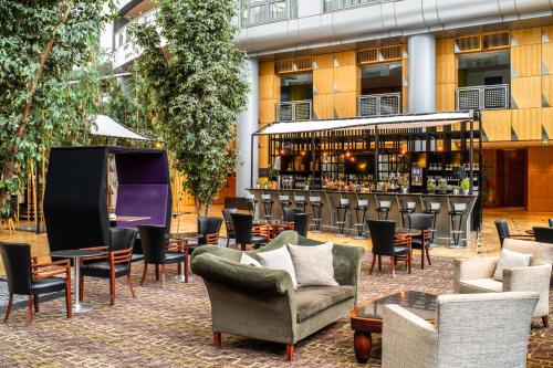 un patio con sillas y mesas y un bar en The Atrium Hotel & Conference Centre Paris CDG Airport, by Penta en Roissy-en-France