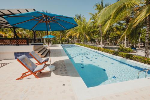 a swimming pool with a blue umbrella and a chair and an umbrella at La Mar de Bien in Buritaca