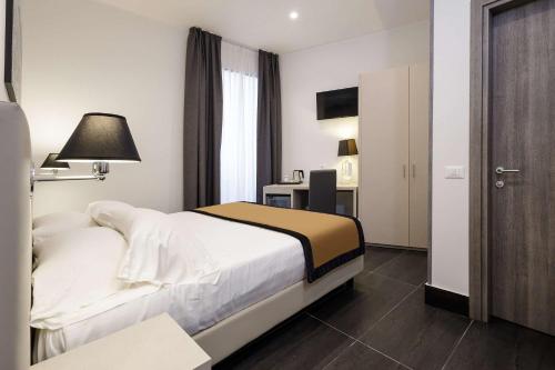 a bedroom with a bed and a desk with a lamp at Best Western Hotel dei Mille in Naples