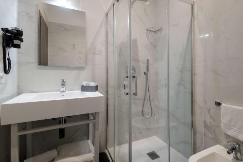 uma casa de banho branca com um lavatório e um chuveiro em Best Western Hotel dei Mille em Nápoles