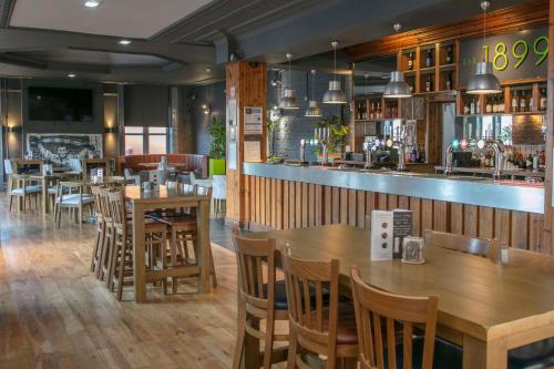 ハートルプールにあるBest Western The Grand Hotel Hartlepoolの木製のテーブルと椅子、バーのあるレストラン