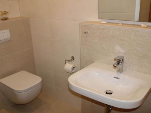 een badkamer met een wastafel, een toilet en een spiegel bij Holiday apartment in Norddeich