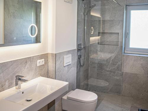 La salle de bains est pourvue de toilettes, d'un lavabo et d'une douche. dans l'établissement Green Residence LM I, à Wildschönau