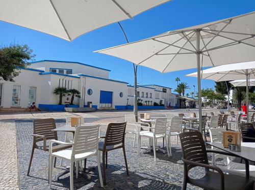 a row of tables and chairs with white umbrellas at CoralBlu, stylish beachside flat - Fast Wi-Fi in Armação de Pêra