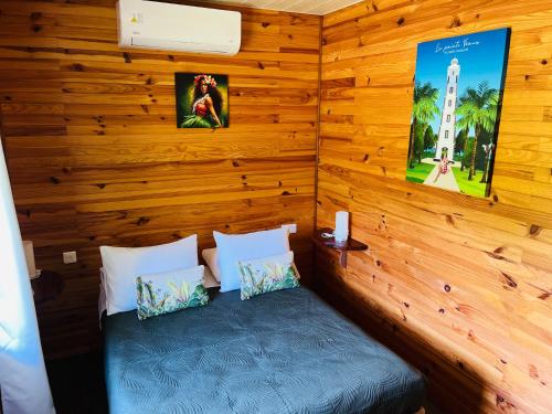 a room with a bed in a wooden wall at Bungalow KURA in Moorea