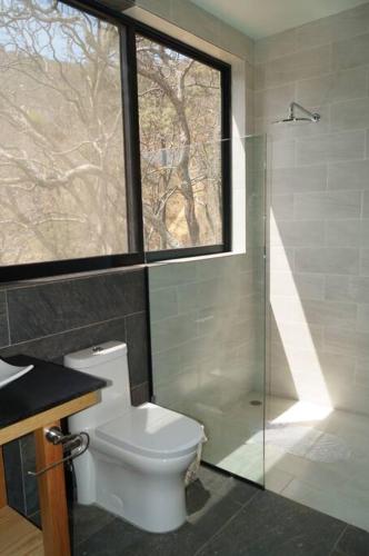 a bathroom with a toilet and a shower and a window at Loft hermoso entre el bosque, vista al Lago. in Valle de Bravo