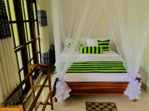 een slaapkamer met een hemelbed met groene en witte kussens bij Ella South Star in Ella