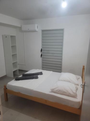 1 dormitorio con 1 cama con sábanas y almohadas blancas en LIBERTY APPART SLM 8 min du centre ville, en Saint-Laurent-du-Maroni