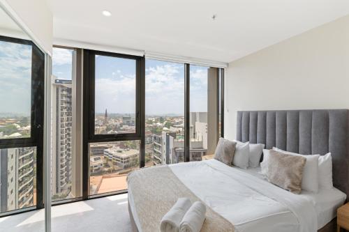a bedroom with a large bed and large windows at Queen St Residence in Brisbane
