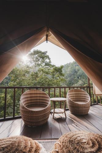 a tent with two chairs and a table on a deck at Glamping tent in Pelaga Eco Park in Patjung