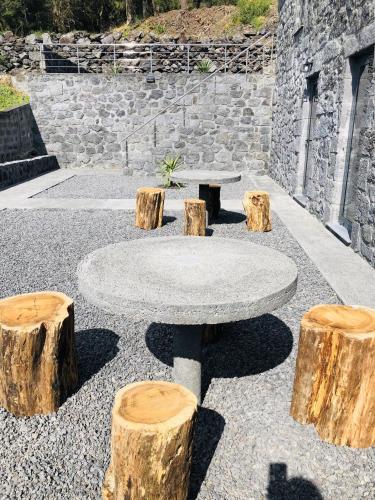 a stone table with three logs around it at AMU- Apartamentos Mistérios da Urzelina in Urzelina