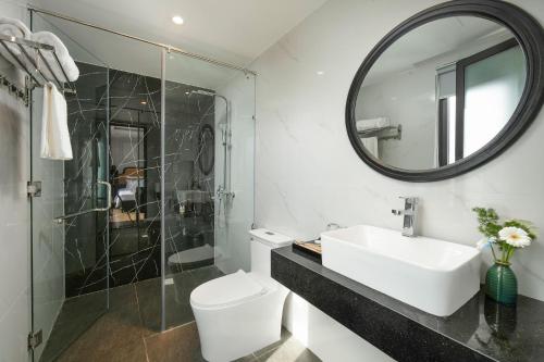 a bathroom with a sink and a toilet and a mirror at Serene Nature Hotel & Spa in Hoi An